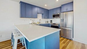Eine moderne Küche mit blauen Schränken, einem Edelstahl-Kühlschrank und einer weißen Arbeitsplatte.