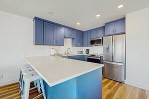 A modern kitchen with blue cabinets, a stainless steel refrigerator, and a white countertop. - Large 2BR Lakeview 1st-Floor - Balcony - Pool (Chelan)