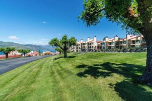 Ein Hotel mit einer Reihe von Gebäuden, einem gepflegten Rasen und Blick auf die Berge im Hintergrund.