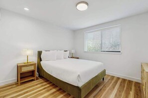 A bedroom with a bed, bedside tables, a window with blinds, and a wooden floor. - Large 2BR Lakeview 1st-Floor - Balcony - Pool (Chelan)