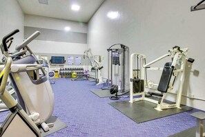 Ett gym med konditionsmaskiner, styrketräningsutrustning och en tv-skärm.