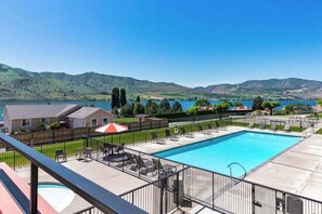 Ein Pool mit Liegestühlen und Blick auf Hügel und einen See.