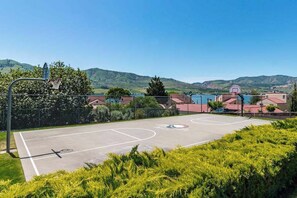 Ein Basketballplatz im Freien mit freiem Blick auf umliegende Häuser und Hügel.