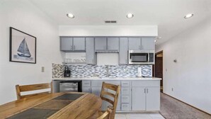 A modern kitchen with grey cabinets, a microwave, and a tiled backsplash. - Quiet 3BR Lakefront - Balcony - Pool (Chelan)