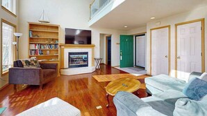 A spacious living room with a fireplace, a bookshelf, and a staircase leading to an upper level. - Sunny 3BR Lakefront - Dock (Chelan)