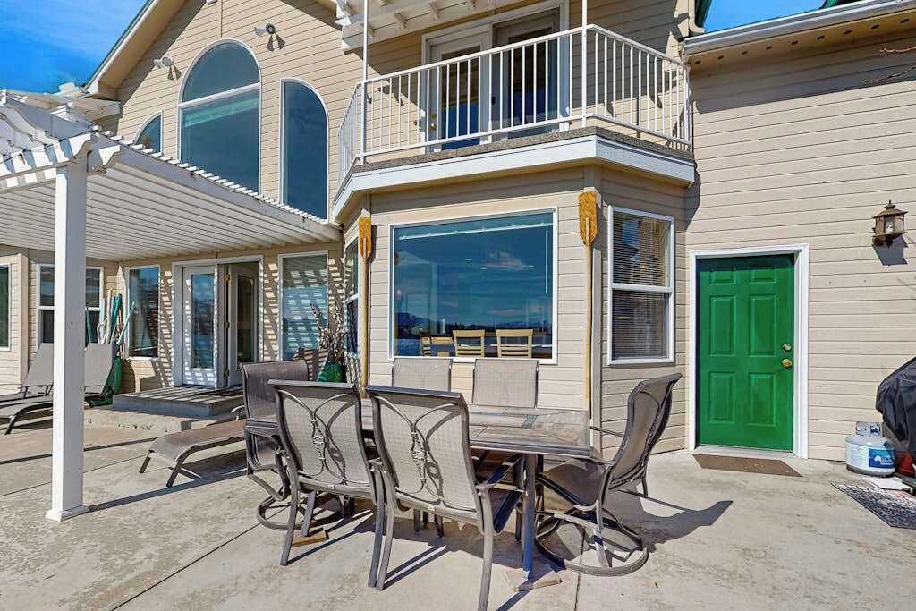 Ein zweigeschossiges Haus mit überdachter Terrasse, einer grünen Tür und einem Balkon.
