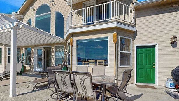 A two-story house with a covered patio, a green door, and a balcony. - Sunny 3BR Lakefront - Dock (Chelan)