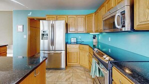 A kitchen with wooden cabinets, a stainless steel refrigerator, a microwave, and a stove. - Sunny 3BR Lakefront - Dock (Chelan)