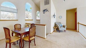 A dining area with a wooden table and chairs, a small seating area with a chair, and a staircase leading to another level. - Sunny 3BR Lakefront - Dock (Chelan)