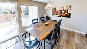 A dining area with a wooden table, chairs, and a pendant light. - Spacious 2BR Mountainview 1st-floor - Patio (Chelan)