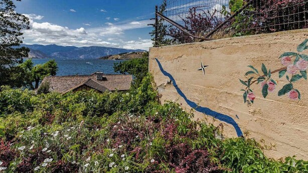 A coastal landscape with a view of the sea, a building with a sloped roof, and a wall with a painted vine. - Spacious 2BR Mountainview 1st-floor - Patio (Chelan)