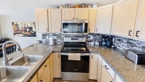 A modern kitchen with stainless steel appliances, a granite countertop, and light wood cabinetry. - Spacious 2BR Mountainview 1st-floor - Patio (Chelan)