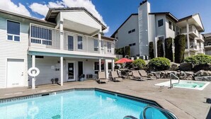 A swimming pool with a covered area, lounge chairs, and a building with a balcony. - Spacious 2BR Mountainview 1st-floor - Patio (Chelan)
