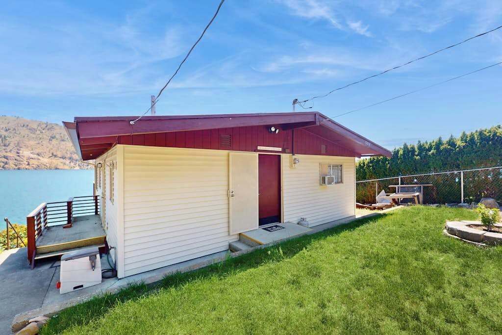 Ein einstöckiges Haus mit rotem Dach, einer kleinen Veranda und einer Tür, die zur Garage führt.