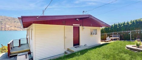 Una casa de un piso con techo rojo, un pequeño porche y una puerta que da a un garaje.