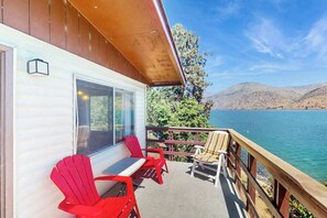 A deck with outdoor seating, a view of a lake, and a mountain in the background. - Lakefront 1BR with large deck, grill, & fast WiFi (Chelan)