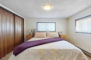 A bedroom with a bed, a window, a bedside table, a nightstand, and a wardrobe.