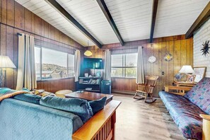 A cozy living room with a wooden ceiling, a sofa, a coffee table, and a bookshelf.