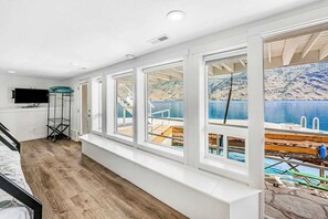 Ein Zimmer mit großem Fenster mit Blick auf einen Steg und Wasser.