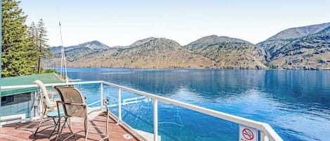 Terraza con piscina que da a un lago, con montañas al fondo.