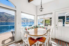Un coin repas avec une table ronde, des chaises blanches et une vue sur la mer.