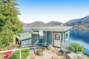 A small cabin with a satellite dish, a stone staircase, and a view of a lake and mountains. - 4BR lakefront cottage & bunk house with dock (Chelan)