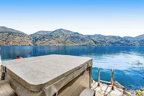 A boat with a covered seating area and a view of a calm lake with mountains in the background.