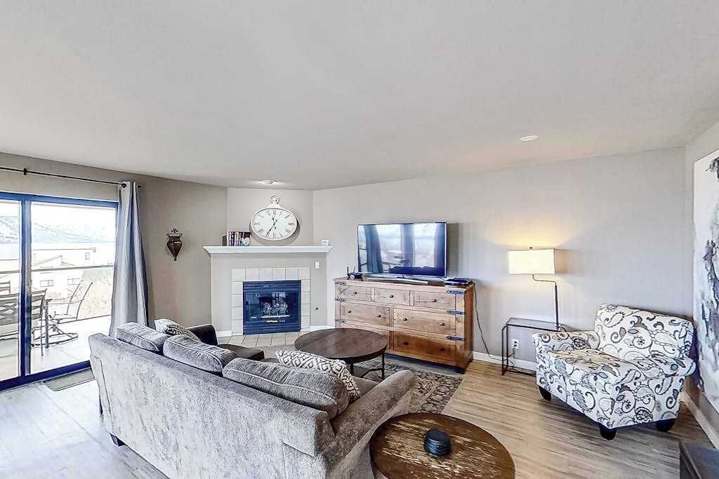 Ein Wohnzimmer mit einer Couch, einem Fernseher, einem Kamin und einem gemusterten Sessel.