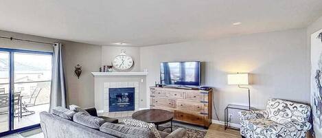 A living room with a sofa, a television, a fireplace, and a patterned armchair.
