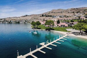 Ein Küsteneigentum mit einer Marina, Gebäuden und einer hügeligen Landschaft im Hintergrund.