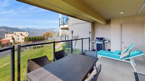 Un balcone con tavolo e sedie, un barbecue e una poltrona da relax.