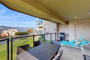 Ein Balkon mit Tisch und Stühlen, einem Grill und einer Liege.