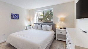 Una camera da letto con un letto grande, due comodini con lampade, una finestra con vista e un televisore a schermo piatto montato a parete.