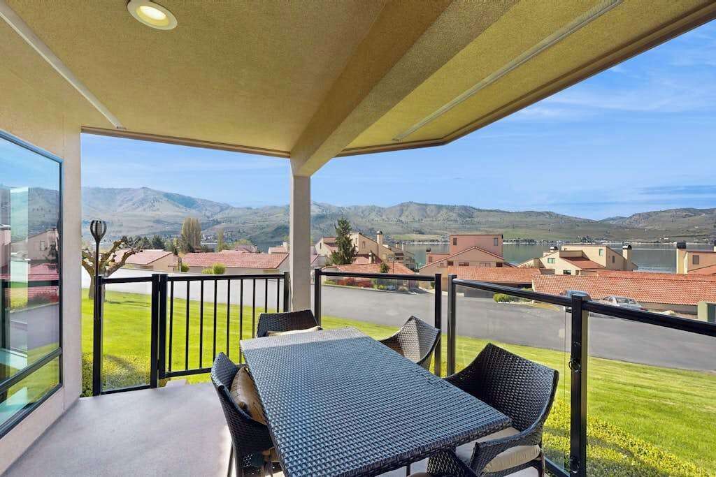 Ein Balkon mit Tisch und Stühlen, der auf ein Wohngebiet mit Häusern und Hügeln blickt.