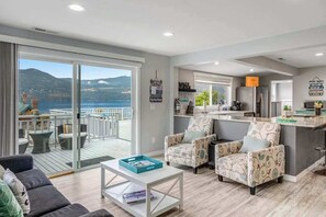 A modern living room with a sofa, armchairs, and a coffee table. A balcony with outdoor furniture is visible. - Walk to Downtown 3BR Lakeview - Hot Tub - Deck (Manson)