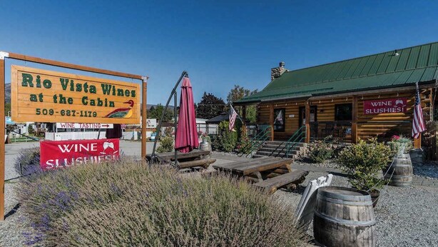 A rustic cabin with a sign for Rio Vista Wines at the Cabin, a wine tasting area, and a wooden structure with a green roof. - Walk to Downtown 3BR Lakeview - Hot Tub - Deck (Manson)