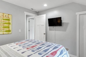 A bedroom with a bed, a television mounted on the wall, and a door leading to another room. - Walk to Downtown 3BR Lakeview - Hot Tub - Deck (Manson)