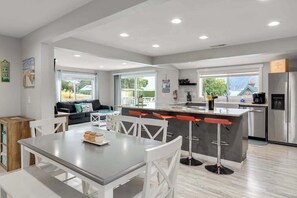 A modern kitchen with a central island, bar stools, and a refrigerator. - Walk to Downtown 3BR Lakeview - Hot Tub - Deck (Manson)
