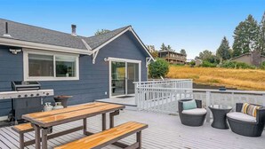 A deck with a grill, picnic table, and outdoor seating. - Walk to Downtown 3BR Lakeview - Hot Tub - Deck (Manson)