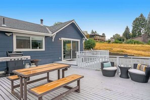 A deck with a grill, picnic table, and outdoor seating. - Walk to Downtown 3BR Lakeview - Hot Tub - Deck (Manson)