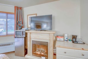 A room with a fireplace, a television, a microwave, and a coffee maker. - Downtown 2BR Mountainview 1st-Floor - Patio (Leavenworth)