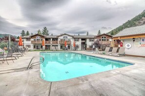 A hotel with a swimming pool, outdoor seating, and a mountainous backdrop. - Downtown 2BR Mountainview 1st-Floor - Patio (Leavenworth)
