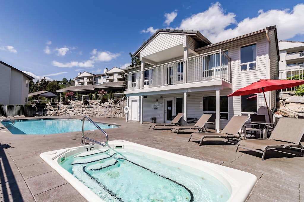 A pool area with lounge chairs and a hot tub.