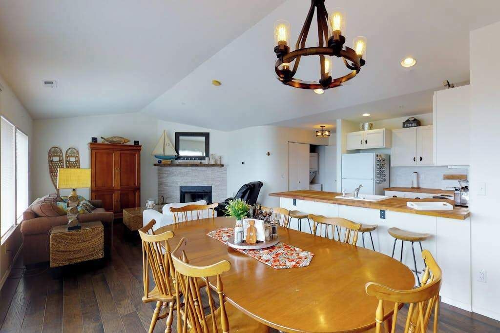 Een moderne keuken met witte kastjes, een centraal eiland en een eethoek met een houten tafel en stoelen.
