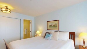 Ein Hotelzimmer mit einem Bett, Nachttischlampen, einer Tür und einem gerahmten Bild an der Wand.