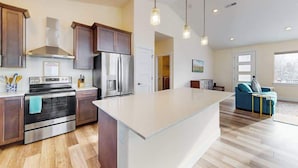 A modern kitchen with stainless steel appliances, wooden cabinets, and pendant lighting. - 3BR water view home with deck & open layout (Manson)