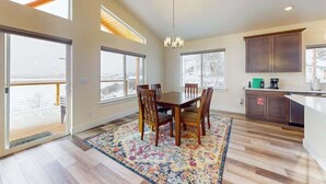 A spacious kitchen with a dining area, large windows, and a view of the outdoors. - 3BR water view home with deck & open layout (Manson)
