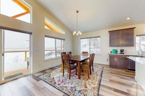 A spacious kitchen with a dining area, large windows, and a view of the outdoors. - 3BR water view home with deck & open layout (Manson)