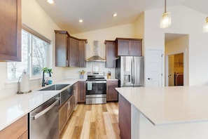A modern kitchen with stainless steel appliances, wooden cabinets, and a large island.