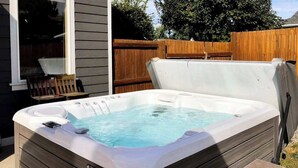 Ein Whirlpool mit Holzverkleidung, einer Steuerung und einer integrierten Sitzgelegenheit.